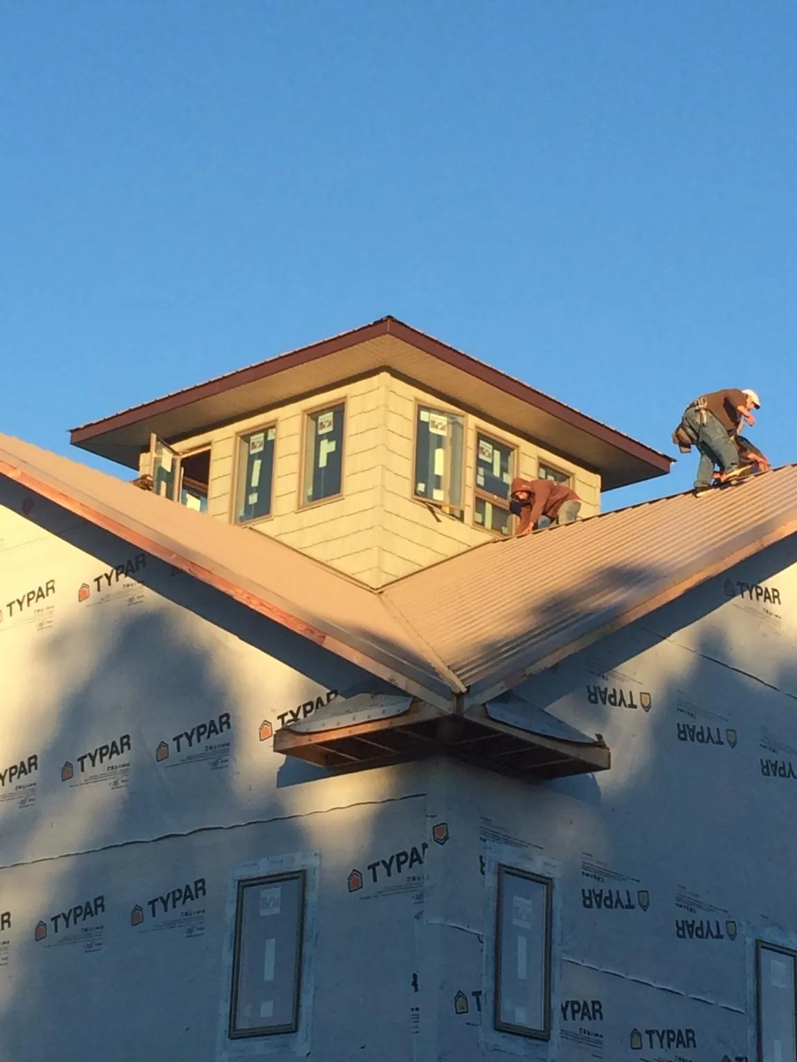 Roofers working around a rooftop cupola on a new metal roof at sunset — Roof Waterproofing in Williamstown by Roofing Brothers